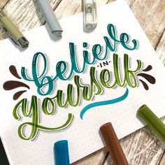 the words believe in yourself written on a piece of paper next to markers and pens