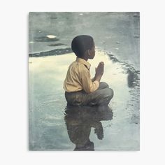 a young boy sitting in the water praying