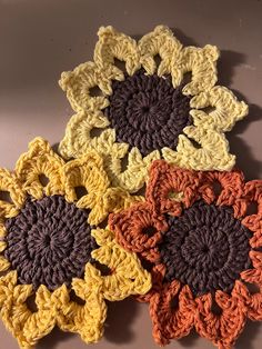 four crocheted flowers sitting on top of a table