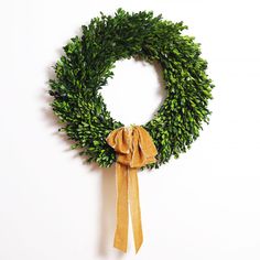 a green wreath hanging on the wall with a bow tie around it's neck