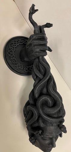 a black sculpture is hanging on the wall next to a light fixture with an intricate design