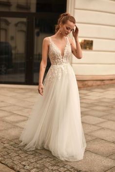 a woman in a wedding dress is walking down the street with her hand on her head