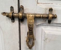 an ornate brass handle on a white door