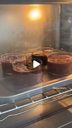 three chocolate pies sitting in an oven with the light shining on them and one is empty