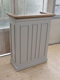 a white cabinet sitting on top of a hard wood floor in front of a window