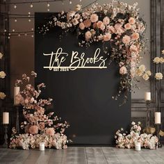 the bridals sign surrounded by flowers and candles in front of a black backdrop