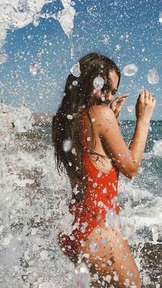 a woman in a red swimsuit splashes water on her face