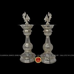 two silver candlesticks sitting on top of each other