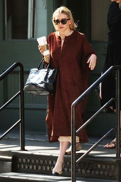 a woman in a red dress is walking down the street with her handbag and coffee