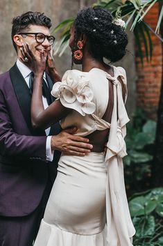 a man in a suit and tie standing next to a woman wearing a white dress