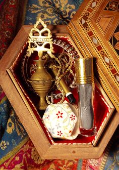 an open wooden box filled with different types of perfumes and other items on top of a rug