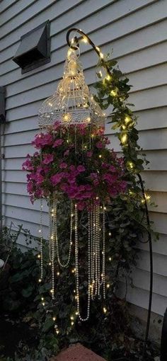 a birdcage with lights hanging from it's sides and flowers in the bottom