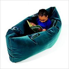 a young boy sitting in a bean bag chair reading a book