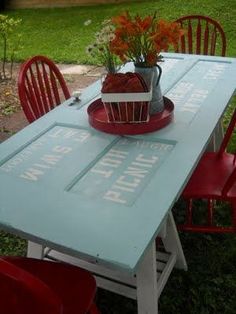 a blue table with red chairs around it and a basket filled with flowers on top