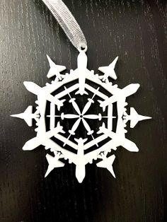 a white snowflake ornament hanging on a black table with silver ribbon