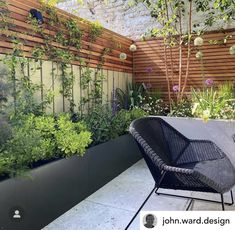 an outdoor seating area with plants growing on the fence and in the background, there is a black wicker chair