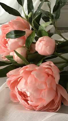 some pink flowers on a white table cloth