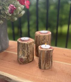 two wooden candles sitting on top of a table next to a vase with flowers in it