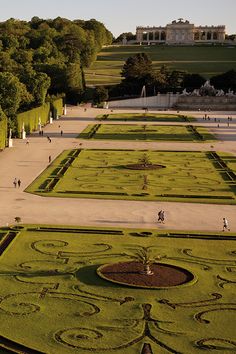 an aerial view of people walking in the middle of a large garden with many hedges