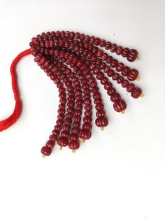 several red beads are on a white surface and one is being held by a string