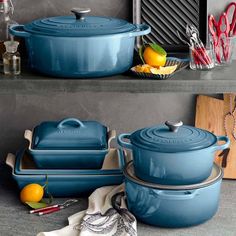 blue pots and pans sitting on top of a counter next to an orange slice