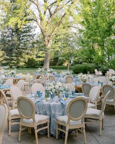 an outdoor wedding reception with blue and white linens, tables set up for dinner