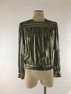 "Fabulous Lloyd Williams very lightweight 1980's black & gold lamé striped pleated blouse with puffed sleeves and slight bishop cuffs. Covered buttons are on the waist, cuffs and shoulder and blouse has shoulder pads that may easily be removed if so desired. The black rayon stripes are sheer and the gold lamé is more opaque. Blouse is in excellent vintage condition. Labeled a size 10, though please do check the measurements 85% rayon 15% metallic thread Shoulders 15\" across Chest 42\" Waist Striped Long Sleeve Party Blouse, Gold Long Sleeve Top For Evening, Gold Blouse For Workwear In Fall, Striped Long Sleeve Party Top, Striped Tops For Fall Party, Retro Long Sleeve Blouse For Evening, Retro Long Sleeve Evening Blouse, Classic Gold Tops For Spring, Vintage Gold Blouse For Party