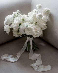 a bouquet of white flowers sitting on top of a couch next to a piece of ribbon