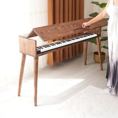 a woman in a white dress is playing an organ with her hands and standing next to a piano