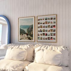 a white couch sitting in front of a window next to a wall with pictures on it