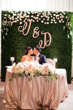 a bride and groom sitting at a table in front of a sign that says u & d