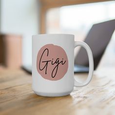 a white coffee mug sitting on top of a wooden table next to a laptop computer