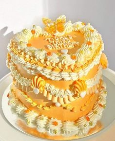 a three tiered cake is decorated with yellow and white icing, butterflies on the top