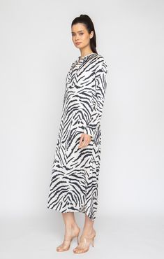 Experience the ultimate comfort and style with the Madagascar Long Sleeve Tunic Dress. This machine-washable dress is crafted from a luxurious, soft, and breathable fabric. The stunning Zabra print adds a touch of elegance, making this versatile dress suitable for both lounging at home and dressing up for a night out. Long Sleeve Tunic Dress Elegant, loose fit Notched neckline Long sleeve with button placket Bottom side slits on both sides Lusciously soft poly-silk blend for ease of care Machine Printed Viscose Midi Dress For Daywear, Long Sleeve Printed Loungewear Dress, Long Sleeve Silk Loungewear Dress, Silk Long Sleeve Loungewear Dress, Long Sleeve Silk Dress For Loungewear, White Silk Dress For Loungewear, Printed Tunic Dress For Loungewear, Long Sleeve Viscose Dresses For Loungewear, White Printed Dresses For Loungewear