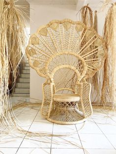 a wicker chair and table in a room with white tiles on the floor, surrounded by dried grass