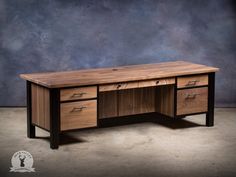 a wooden desk with two drawers in front of a blue wall and concrete flooring