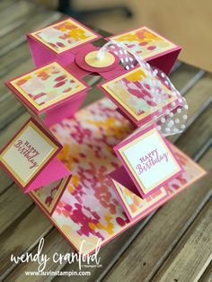 a pink and yellow birthday card holder on a wooden table