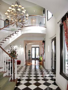 the foyer is decorated in black and white checkerboard flooring with chandelier