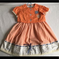 Handmade Dress Set In Size 4t. It Is An Orange Gingham Dress And Jacket. Sleeveless Bodice Has A Flower Patter With A Back Button Closure. There Is A Contrasting Fabric On Arm Hole Trim. Orange Gingham Skirt Has Full Skirt Contrast Detail On Hem With Lace And Blue Ribbon. Back Bodice Has Button Belt Detail. Jacket Has Short Sleeves With Lace Trim And A 3 Button Closure And Crochet Flower Trim. Dress Measures, Shoulder To Shouler 9 1/2" Waist Is 22" And Shoulder To Hem Is 22" Orange Gingham, Gingham Skirt, Dress And Jacket, Handmade Dress, Gingham Dress, Handmade Dresses, Crochet Flower, Dress Set, Size 4t