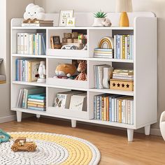 a white book shelf filled with lots of books on top of a hard wood floor