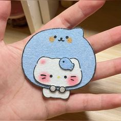 a hand holding a blue and white hello kitty sticker