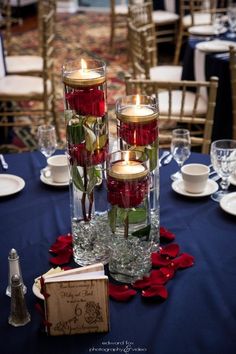 two vases filled with roses and candles on top of a blue cloth covered table