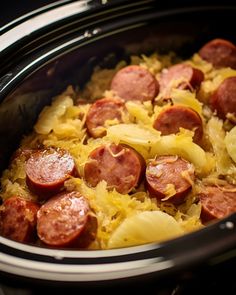 a crock pot filled with cooked sausage and noodles