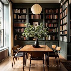 a dining room with bookshelves, chairs and a table in front of it