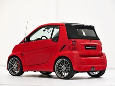 a red smart car parked in a white room