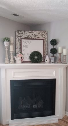 a white fireplace with candles and wreaths on top