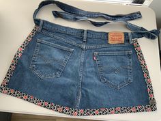 a pair of blue jean shorts with an orange and white flower design on the side