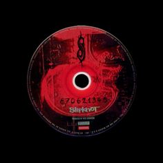 a red disc with black writing on the front and bottom cover, in dark background