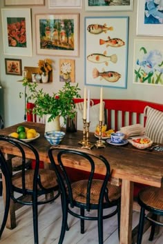 a dining room table with chairs and pictures on the wall above it, along with plates of food