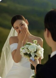 a woman in a wedding dress is looking at the man who is covering his mouth